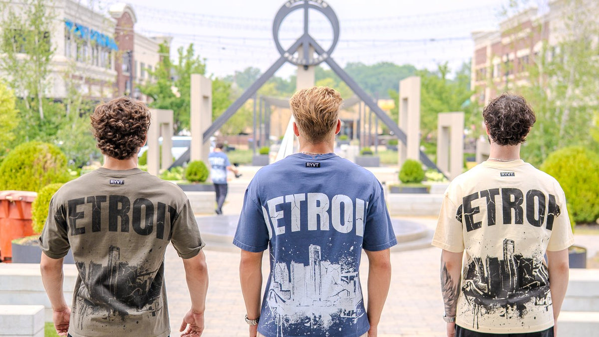 Three models walking away across a Metro Detroit plaza in the Detroit Renaissance Heavyweight Tee, Army Green, Blue and Cream